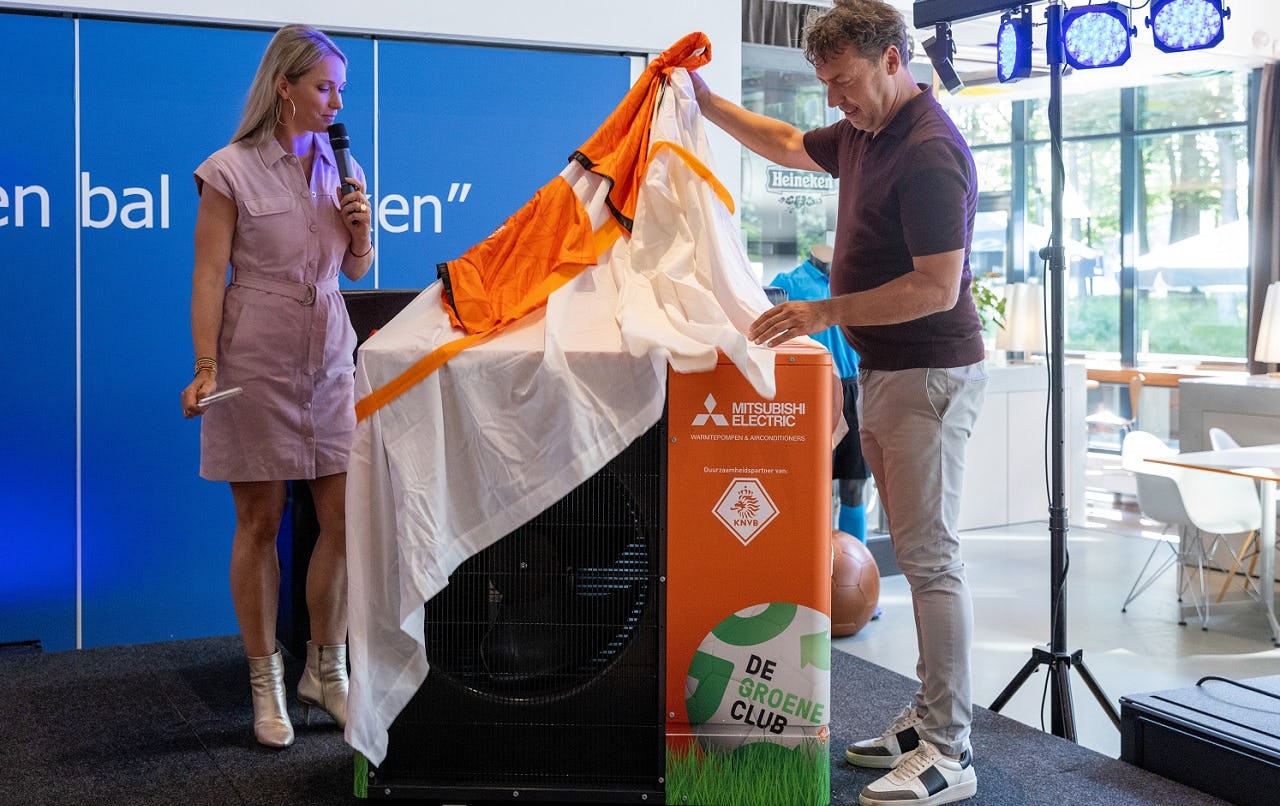 Arjen de Jong onthult de CO2-warmtepomp voor de clubhuizen. Links van hem staat Hélène Hendriks (presentatrice van het event). Foto: Tjapko de Heus.