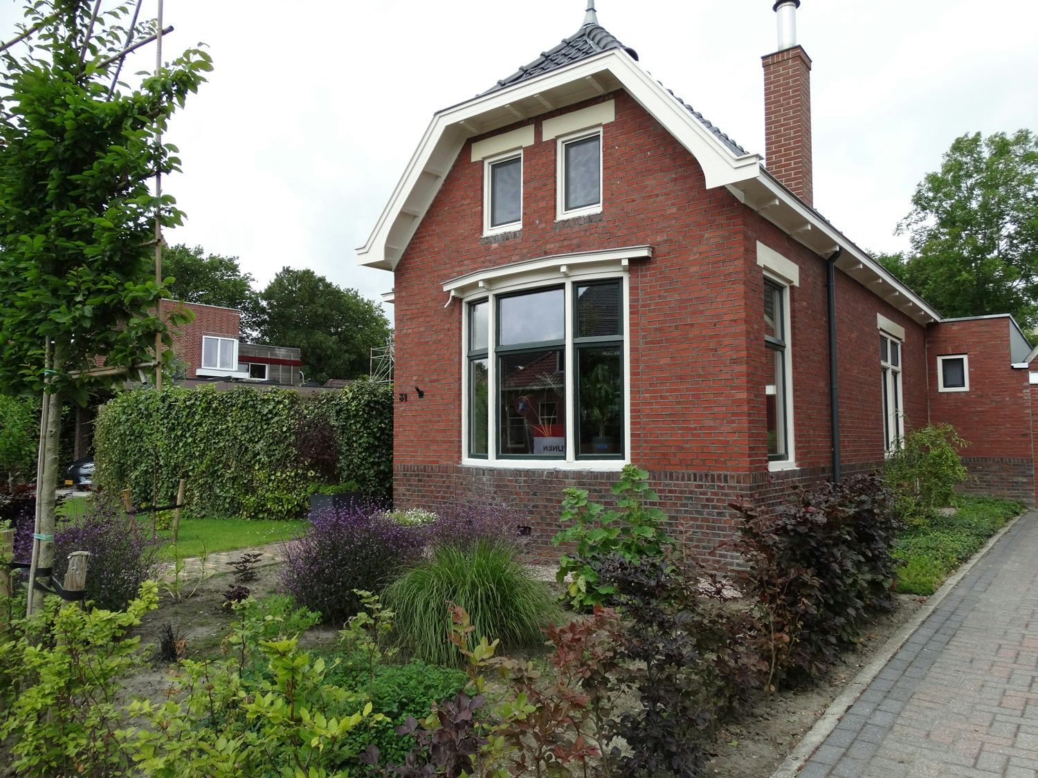 In de voorgevel zijn nieuwe houten kozijnen geplaatst. “We hechten veel waarde aan de uitstraling van het huis.” De schoorsteen rechts is de afvoer van de houtkachel. 