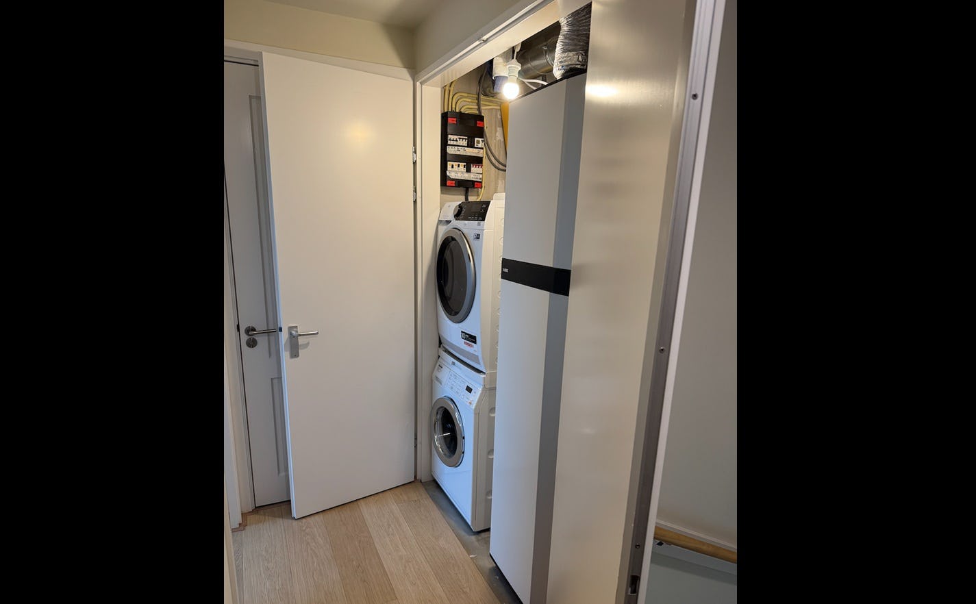 De warmtepomp met geïntegreerde tapwaterboiler naast de wasmachine en de droger. 