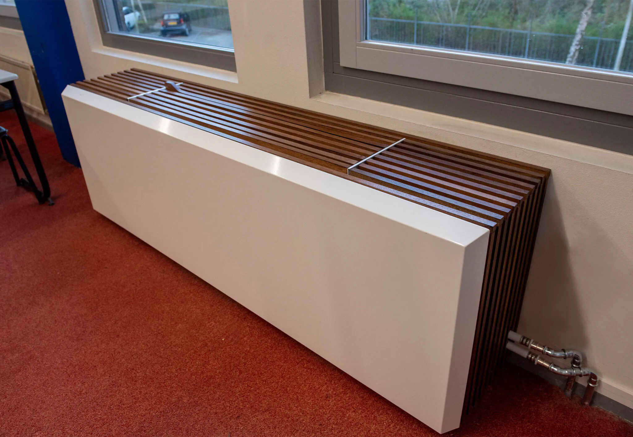 Met de stalen voorkant en houten lamellen ombouw lijkt de Goflow ForSeasons op een grote convectorradiator.