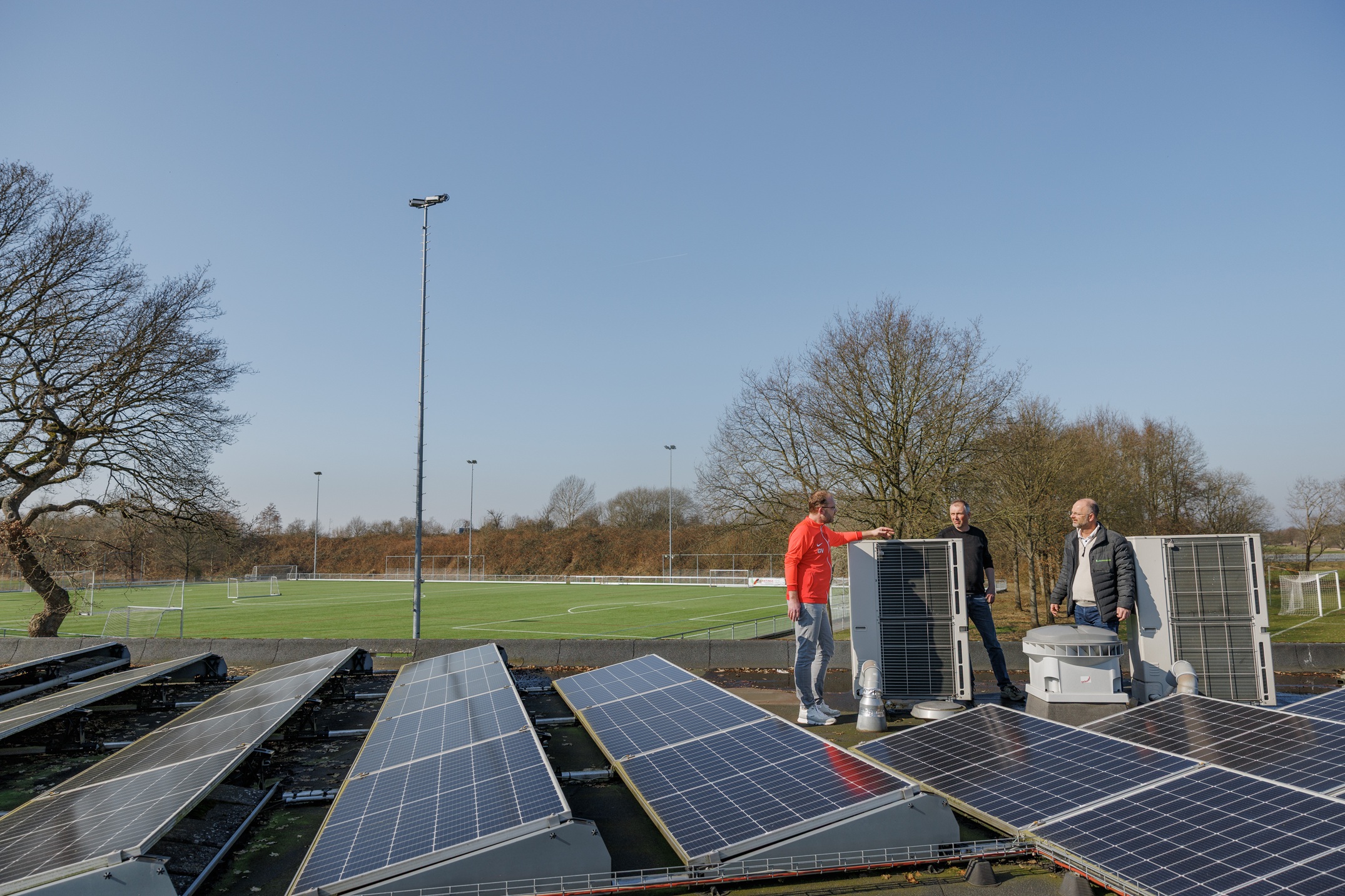 Het dak van het sportcomplex met zonnepanelen en de buitendelen van de warmtepompinstallatie.
