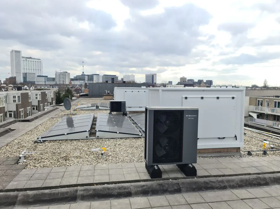 De twee hybride warmtepompen van Itho Daalderop op het dak van de portiekflat. Achter elke warmtepompen staat een witte kast, met daarin onder meer het binnendeel van de warmtepomp.  