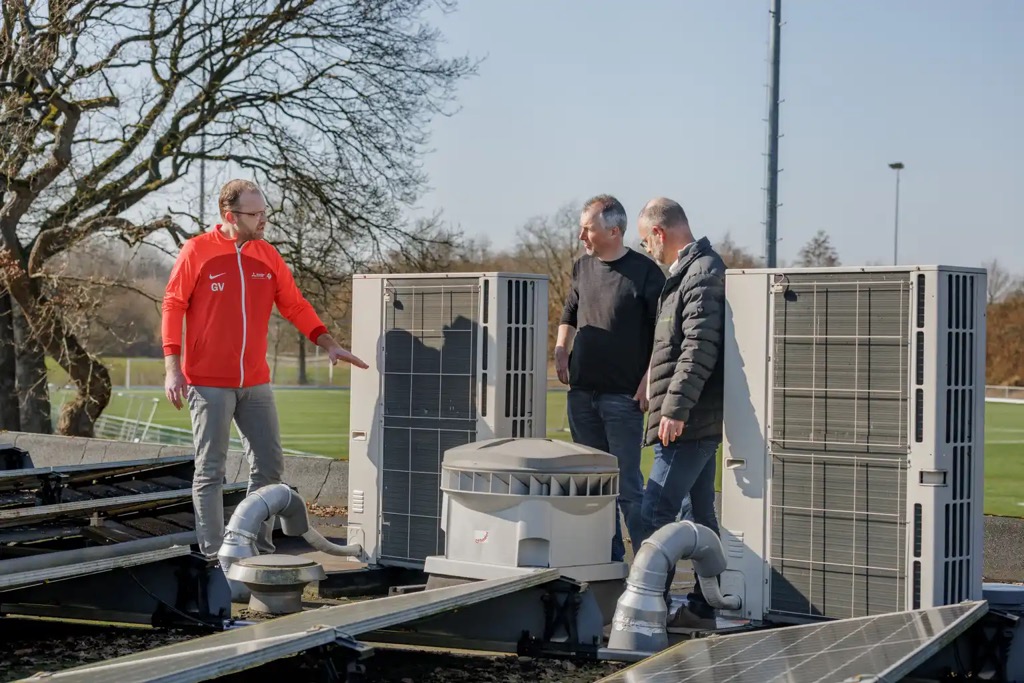 Gert Veulink (links) bij de warmtepompen van Sportpark Noord-West in Beilen. Samen met buffervaten en zonnepanelen bespaart het sportpark daarmee 6.000 m³ aardgas per jaar.