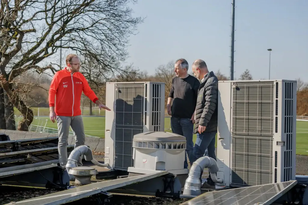 Gert Veulink (links) bij de warmtepompen van Sportpark Noord-West in Beilen. Samen met buffervaten en zonnepanelen bespaart het sportpark daarmee 6.000 m³ aardgas per jaar.