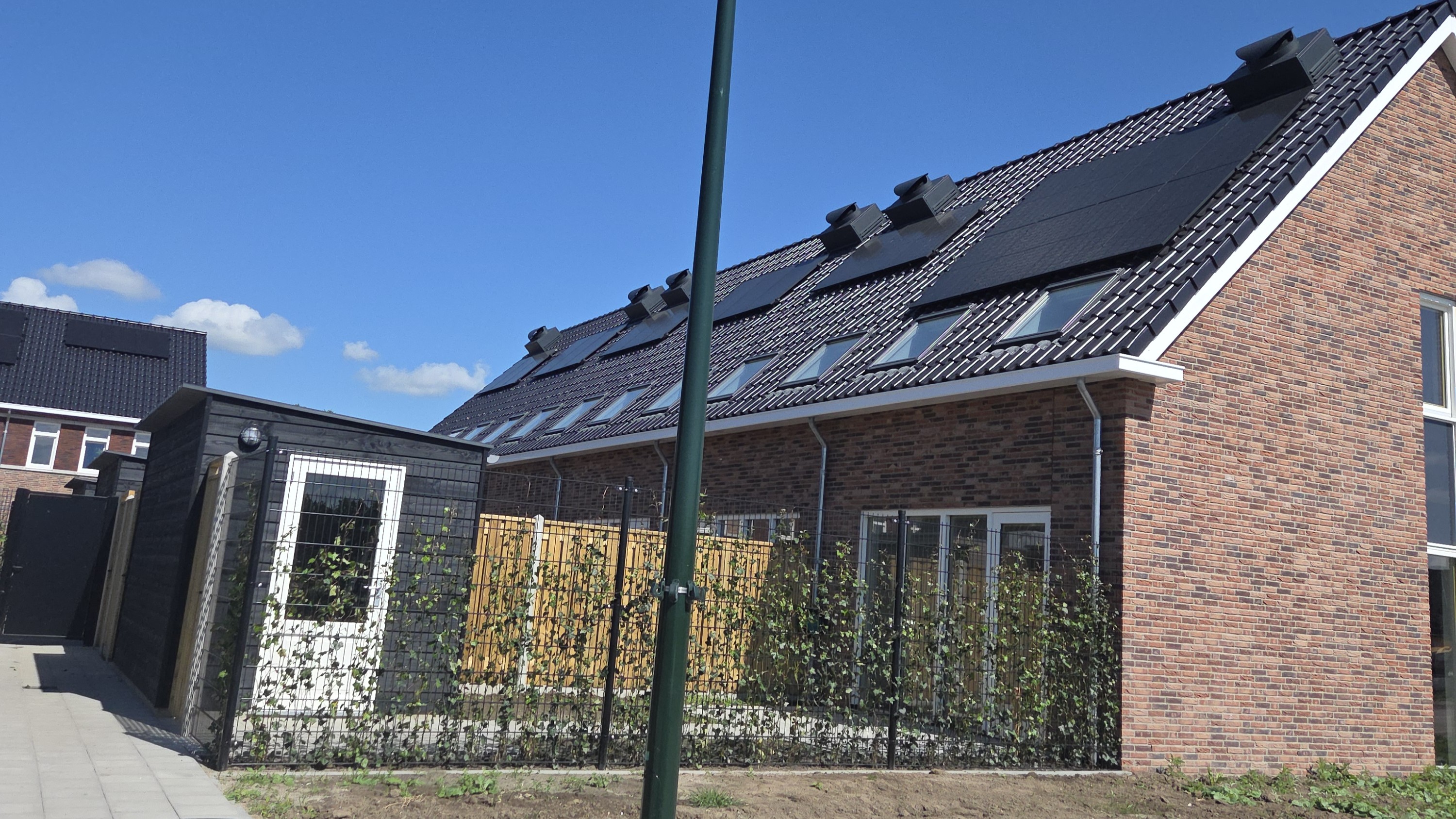 De drycoolers op het dak van een rijtje nieuwbouwwoningen.